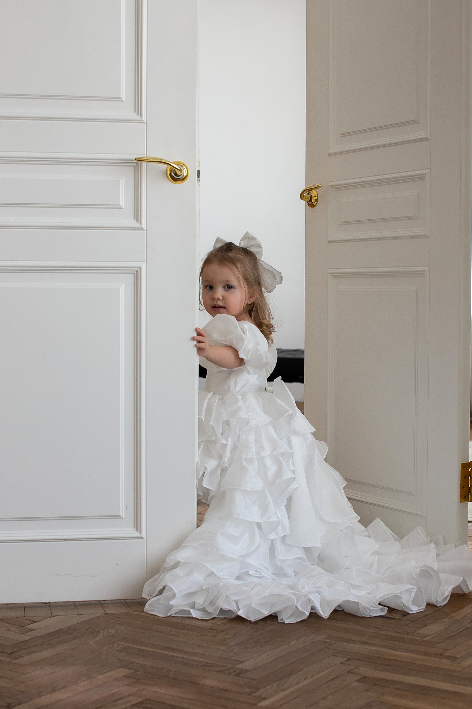Fille de 2 ans habillée d’une robe blanche longue avec plusieurs étages et traîne