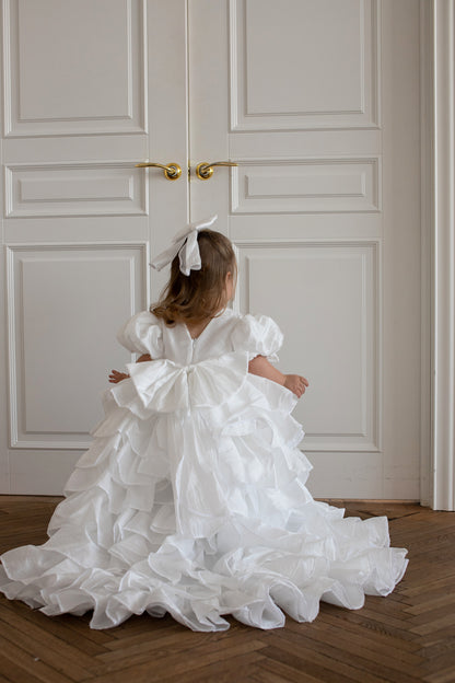 Jeune enfant portant une robe blanche volumineuse à étages avec traîne