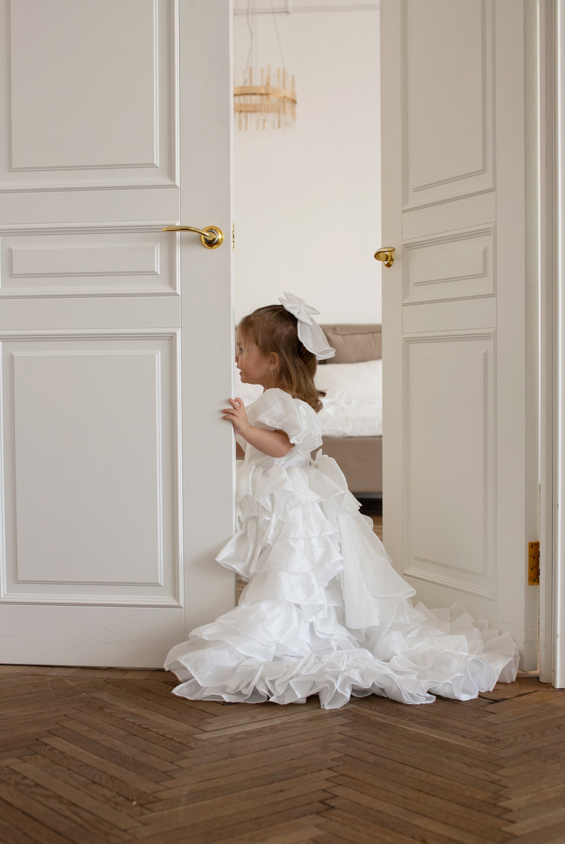 Petite fille en robe blanche cérémonie avec jupe à étages et longue traîne