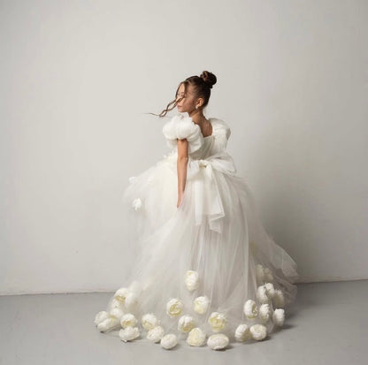     Robe de cérémonie enfant avec longue traîne ornée de fleurs séchées et manches bouffantes.
